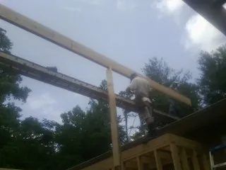 Carpenter setting a ridge beam over a new addition frame — Ice Dam Removal by Roofing Brothers in Amana