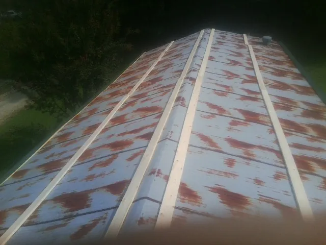 Rusted metal roof panels with new wood purlins before replacement — Storm Damage Roof Repair in Amana by Roofing Brothers