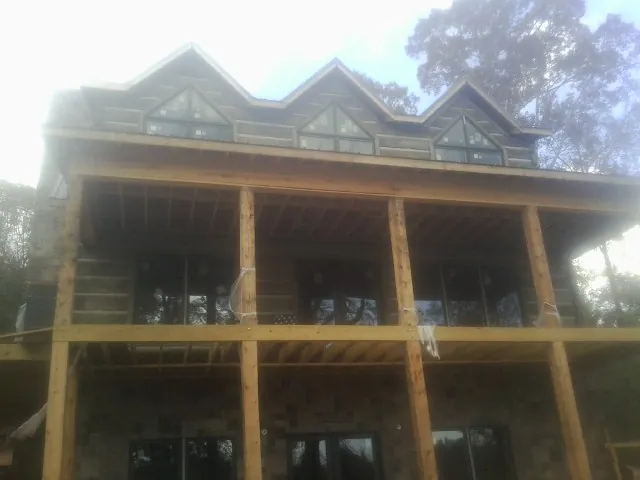 Dormers and porch framing on a large log home under construction — Roof Coating work by our crew in Amana