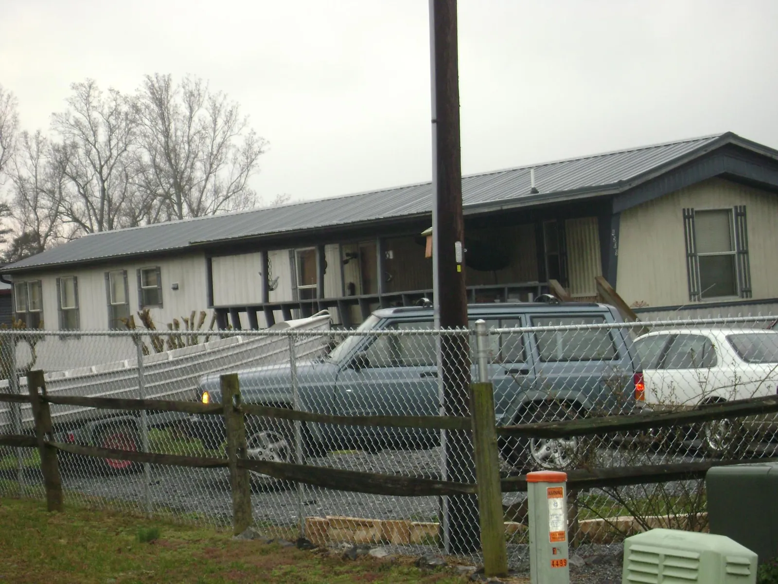 Dark metal roof on a long single story building behind a chain link fence in Amana