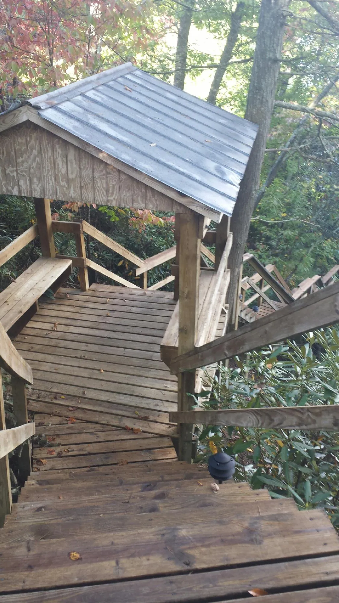 Metal roofed shelter over wooden steps on a wooded walkway — Skylight Repair & Installation work by our crew in Amana