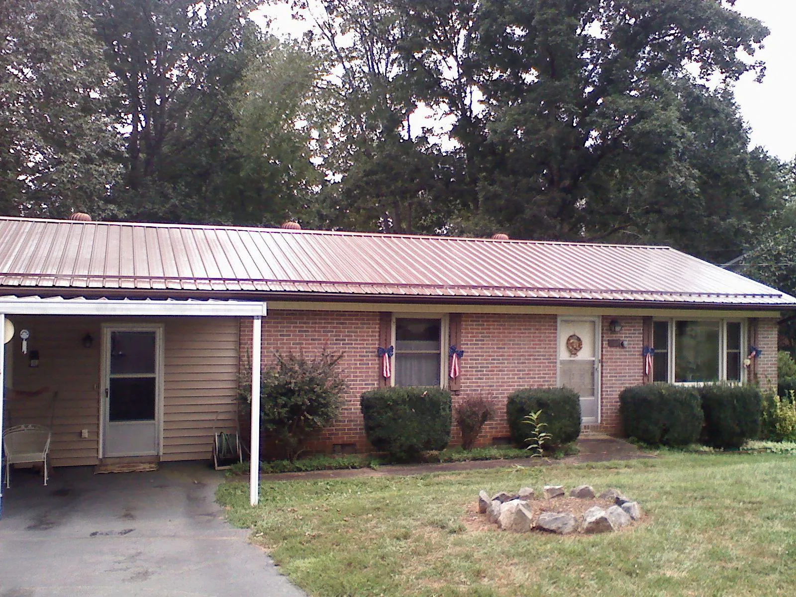 Bronze metal roof and carport on a brick ranch home — Roof Repair work by our crew in Amana